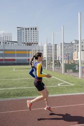 Running young woman in sportswear on stadium