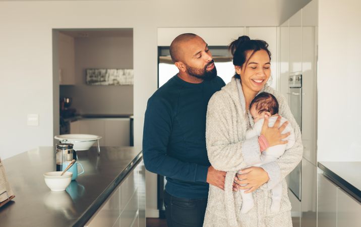 Happy couple with their little baby boy in kitchen