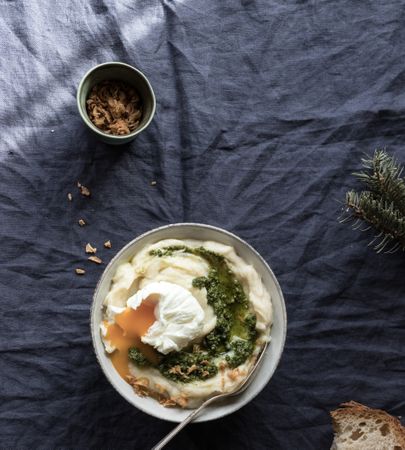 Person holding bowl with cauliflower puree with pesto and eggs
