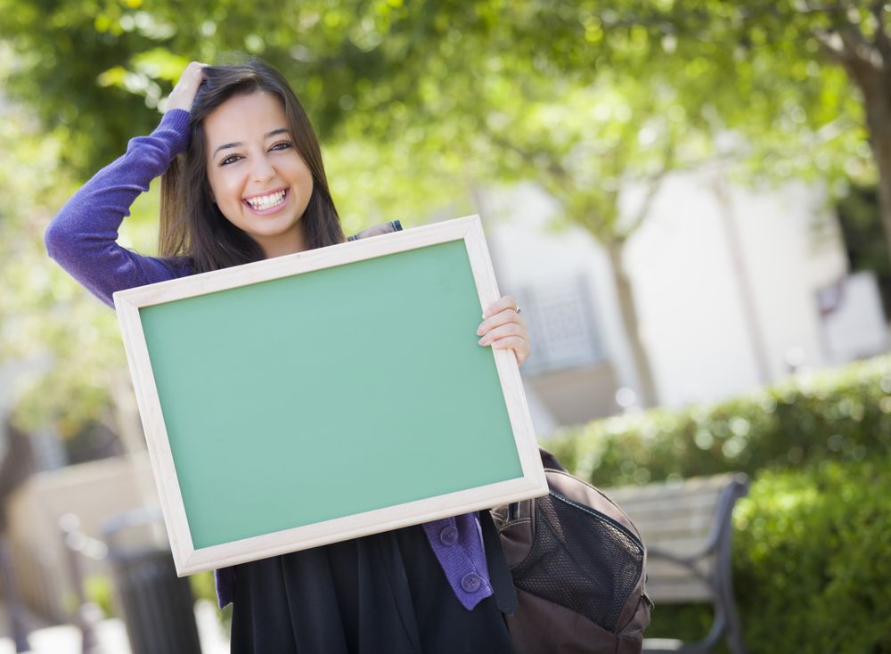 Smiling Female Student Holding Blank Chalkboard