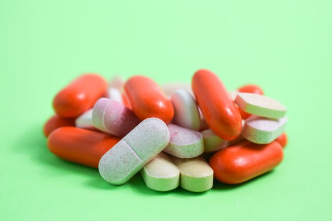 Variety of colorful medication and vitamins on green table with copy space