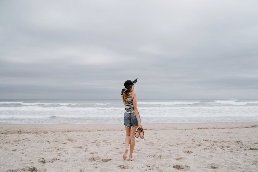 Young female walking barefoot on sandy beach