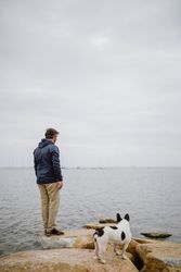 Owner and dog on stones near sea