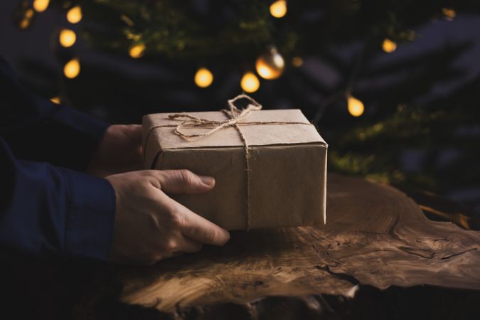 Man holding Christmas gift by wooden table