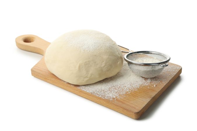 Board with dough and flour isolated on plain background