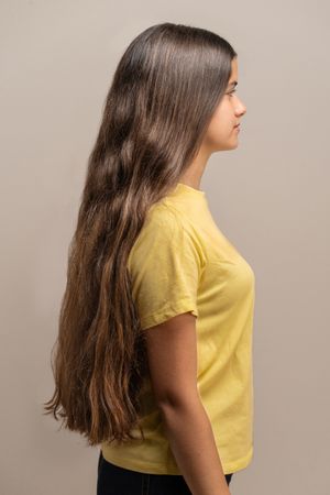 Side view profile of a young woman with very long brown hair.