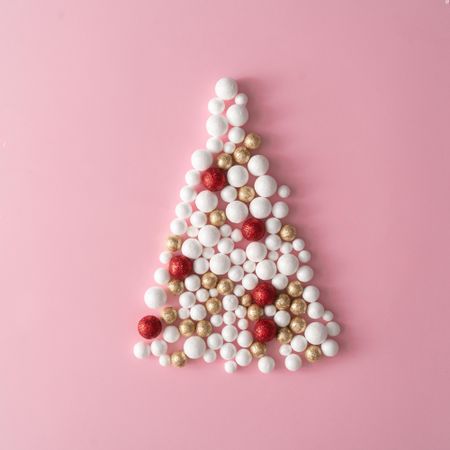 Christmas tree made of gold and red glitter ball decoration on pink space