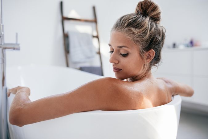 Close up shot over the shoulder of young woman in bathtub