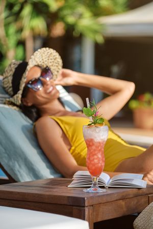 Happy woman relaxing with cocktail on table
