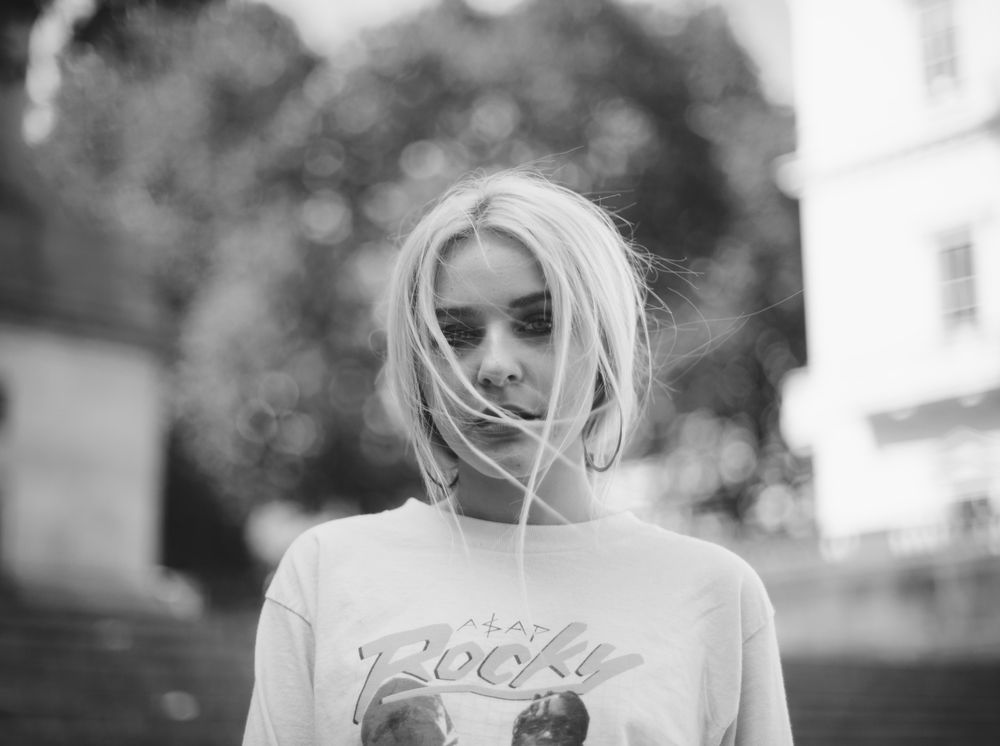 Young white woman with bleached blonde hair covering face standing casually