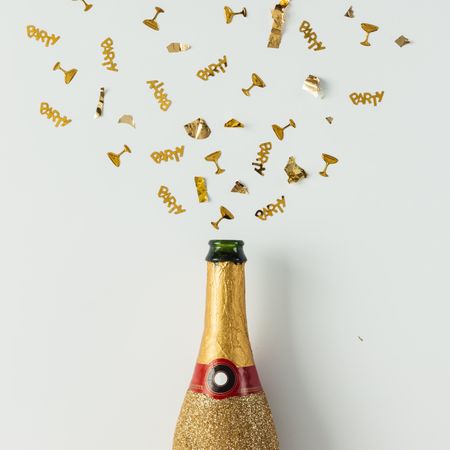 Golden champagne party bottle on light  background with gold confetti