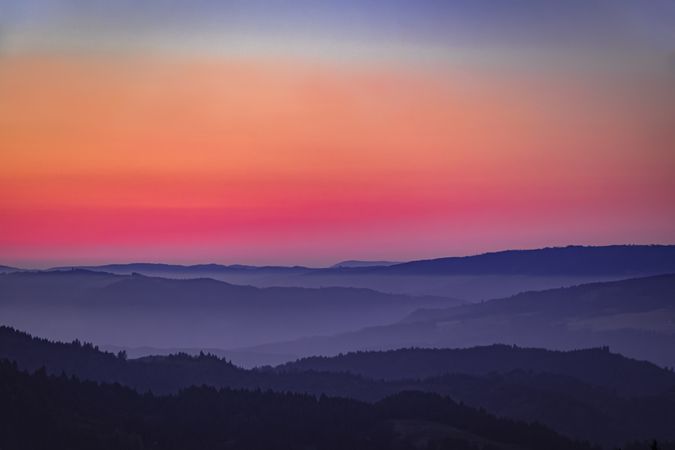 Colorful sunset over tree lined hills on the West Coast