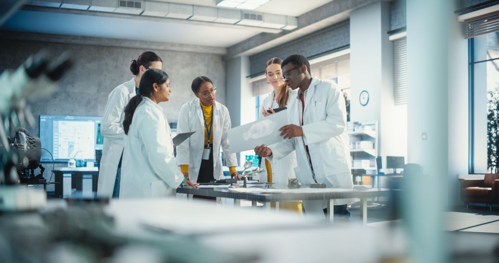 Engineers In Lab Coats Using Laptop Computer and Tablet, Brainstorming Ideas For Electronic Components