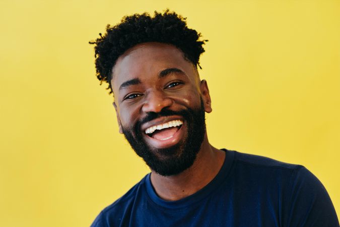 Portrait of smiling Black man in navy t-shirt in bright colored studio