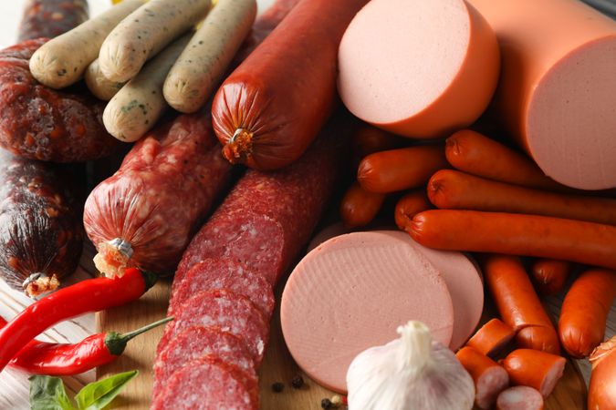 Top view of a variety of cured meats and bulb of garlic