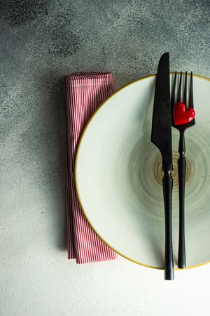 Ceramic plates with red napkin, cutlery and heart decoration