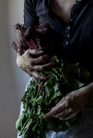 Faceless person with bunch of beetroots and key