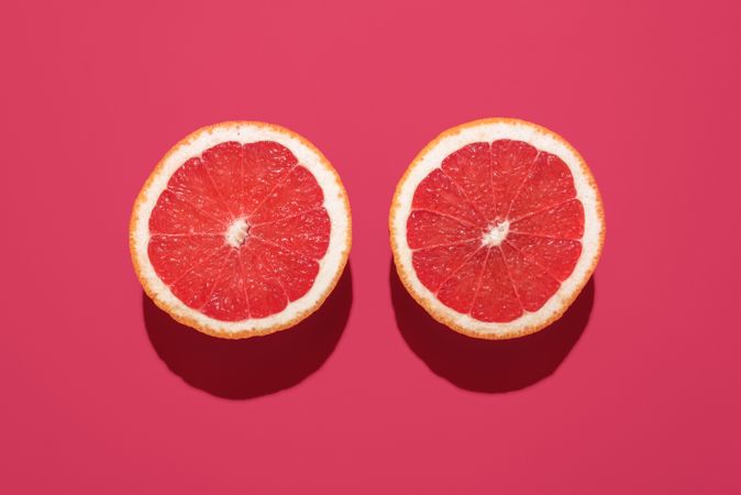 Grapefruit sliced in half minimalist on a magenta background