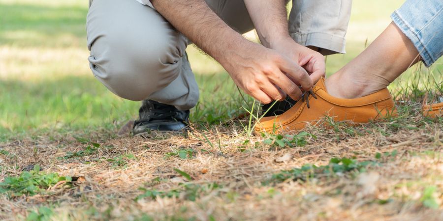 Close up of man tying shoe of woman in park