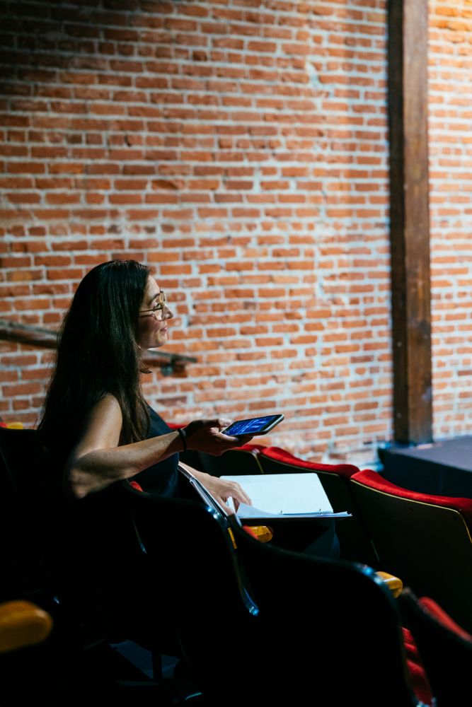 Woman sitting in theater with script and phone