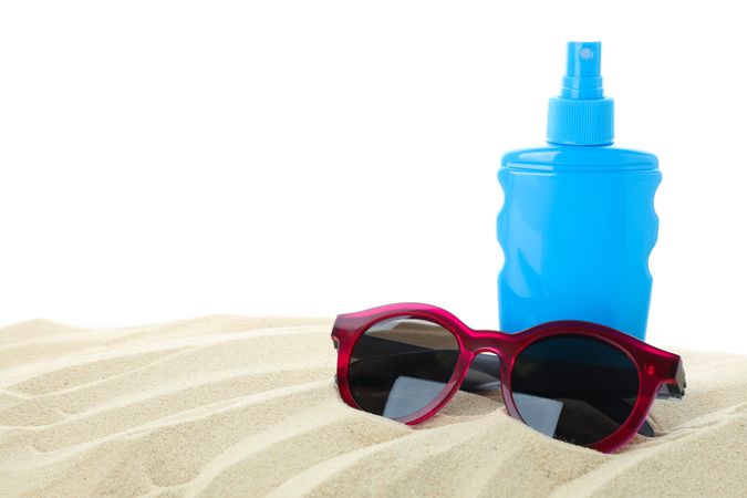 Sunscreen with sunglasses on clear sea sand isolated on blank background. Summer vacation