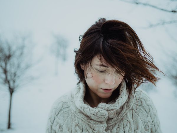 Dreamy woman in sweater against winter landscape