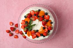 Berry cream cake on pink background. Delicious dessert