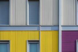 Facade of modern multicolored building with narrow windows