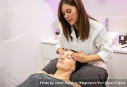 Beautician massaging face of female client in beauty salon 432jRV