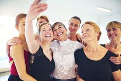 Group of women pose for selfie in bright dance studio
