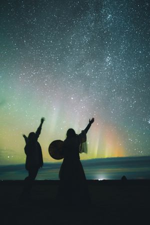 People dancing near sky in stars and polar lights at night