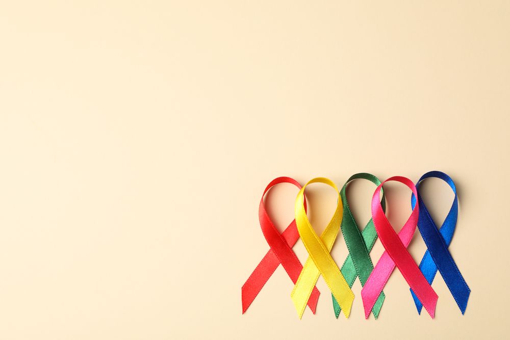Flat lay composition with awareness ribbons on color background, space for text.