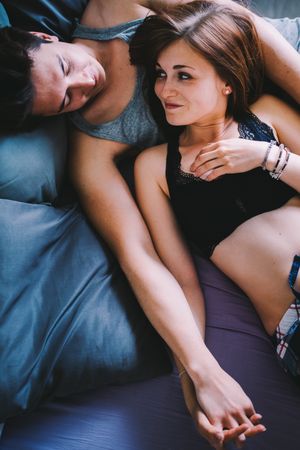 Young man and woman lying down together looking lovingly at each other
