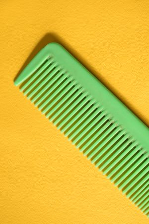 Bright green hair comb on yellow background