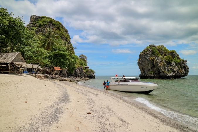 People standing beside boat on seashore