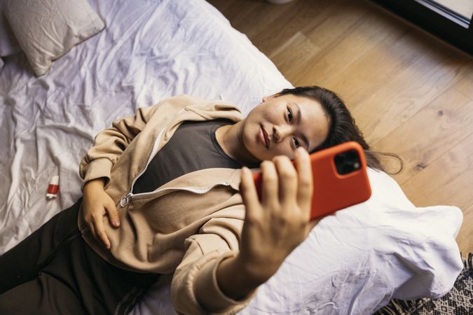 Young Asian woman using a phone on bed
