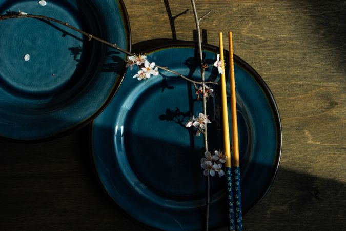Top view of table setting with chop sticks on ceramic navy plate and decorative cherry blossom branch