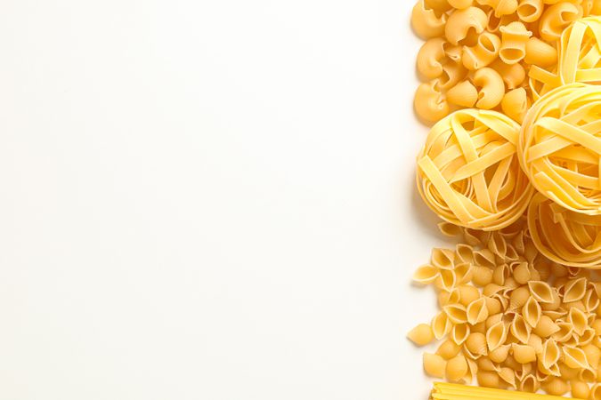 Different pasta on blank background, space for text. Dry uncooked whole pasta