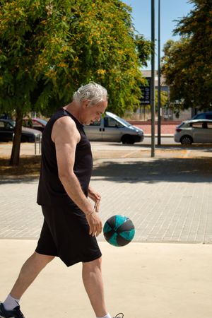 Middle aged man playing basketball on a street court