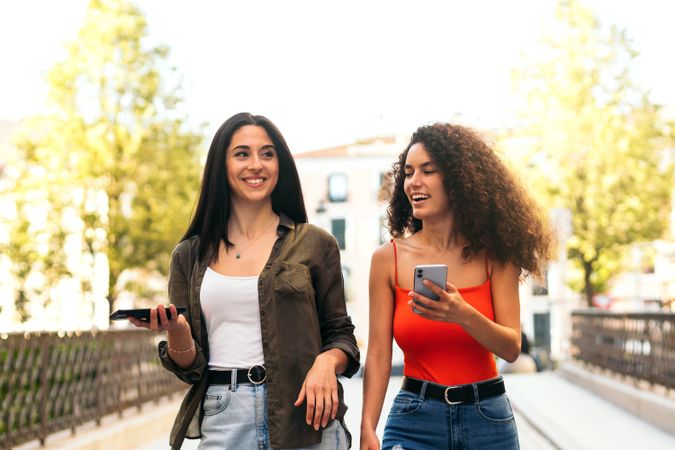 two young women walking and using her mobiles