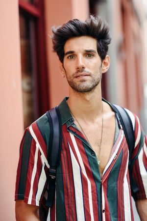 Attractive man with dark hair standing outside looking in the distance