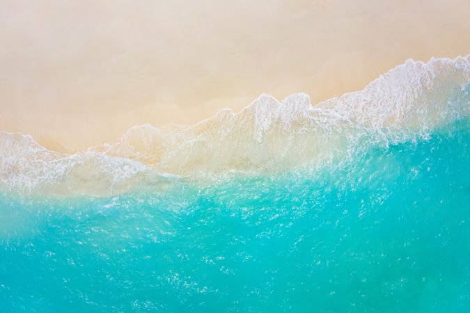 Aerial shot of waves coming up on a tropical beach