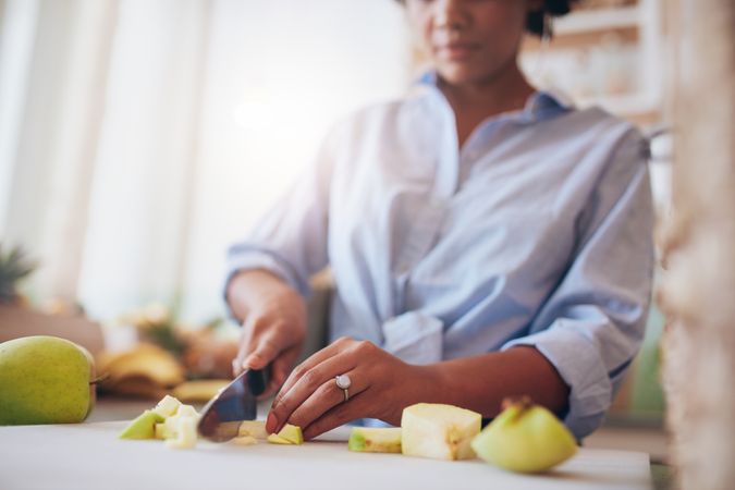 Cropped shot of female hands chopping fruits on the counter