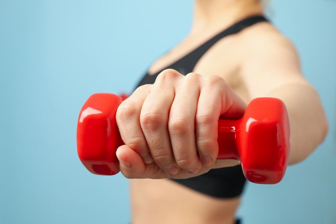 Woman holds red dumbbell, close up. Healthy lifestyle
