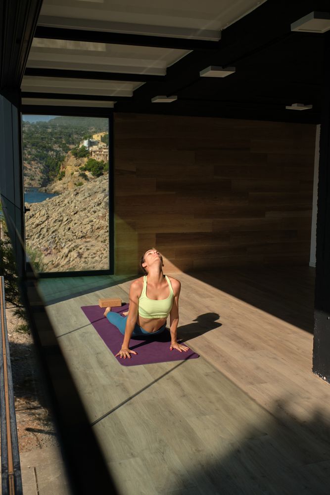 Slim woman practicing yoga in Cobra pose at home