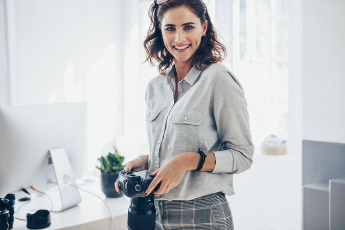 Confident female photographer holding professional camera