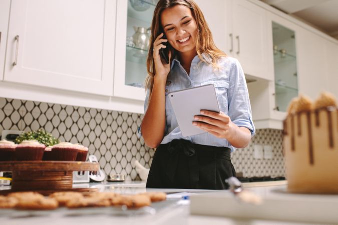 Happy chef in kitchen smiling using digital tablet and talking on phone