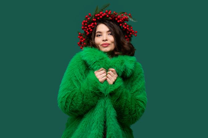 Playful woman in green coat and berry wreath