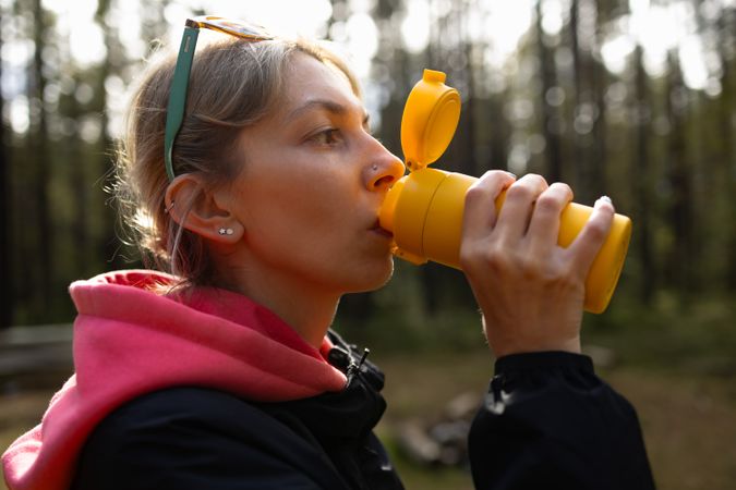 Woman drinking from travel mug outdoors