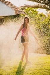 Cheerful teenager having fun with jet of water